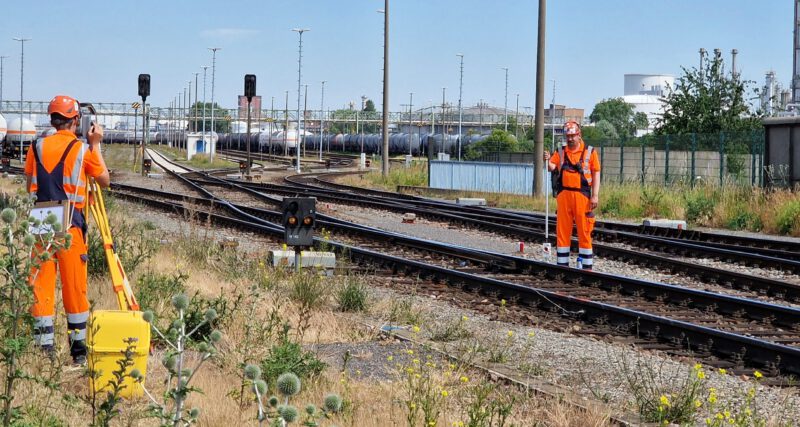 Zwei Vermessungstechniker messen/ stecken an der Gleise was ein/ab